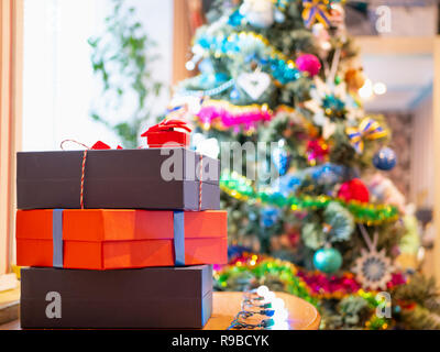 few gift presents boxes near Christmas tree blurred on background. selective focus on boxes. indoor closeup image Stock Photo