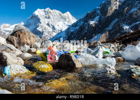 Plastic and other rubbish from a trekker's lodge thrown in a glacial stream in the Nepal Himalayas Stock Photo