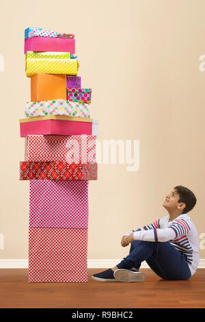 Young Boy sitting on floor Looking up to Christmas presents