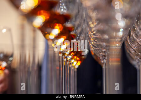 Professional man cavist takes wine glass with cognac from shelf in liquor store. Concept of degustation spirits: whiskey, brandy, rum, sherry, porto,  Stock Photo