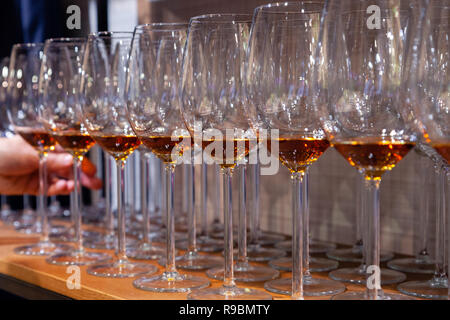 Professional man cavist takes wine glass with cognac from wooden shelf in liquor store. Concept of degustation spirits: whiskey, brandy, rum, sherry,  Stock Photo