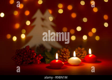 Christmas candles and ornaments over red dark background with lights Stock Photo