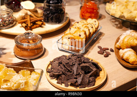 Closeup bakery and snacks, dried fruits, pieces parmesan cheese, honeycombs, dark chocolate, cinnamon sticks, raisin biscotti. Concept degustation pre Stock Photo