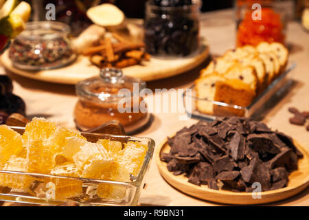 Closeup bakery and snacks, dried fruits, pieces parmesan cheese, honeycombs, dark chocolate, cinnamon sticks, raisin biscotti. Concept degustation pre Stock Photo