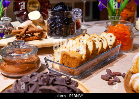 Closeup bakery and snacks, dried fruits and nuts in glass bowls, cinnamon, plate with raisin biscotti. Concept degustation luxury banquet at the prese Stock Photo