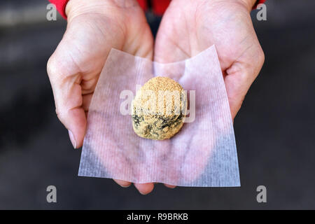 Woman hands holding and showing green mochi cake, sticky glutinous Japanese rice cake dessert, at traditional market in Kyoto, Japan Stock Photo