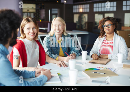 Cheerful coworkers communicating at staff meeting Stock Photo
