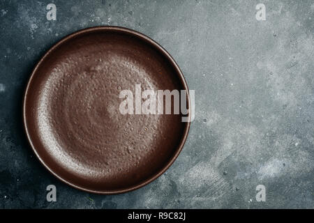 Brown empty plate (handmade ceramic) on gray stone background. Copy space. Stock Photo