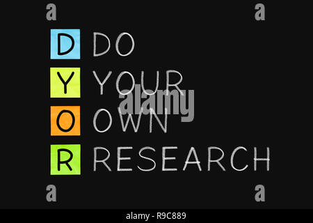 Acronym DYOR - Do Your Own Research handwritten with white chalk on blackboard. Stock Photo