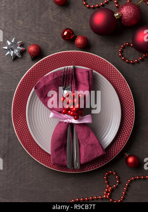 Christmas table place setting with empty gray and red plates, with festive decorations berries and Christmas toys at wooden table. Christmas Xmas New  Stock Photo
