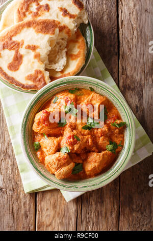 Indian food spicy karhai chicken in tomato sauce close up and naan on the table. Vertical top view from above, rustic style Stock Photo