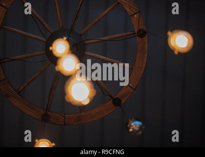 Abstract shot of lightbulbs hanging from a cartwheel on the ceiling of a restaurant Stock Photo