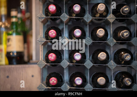 Wine Rack stocked with well ordered wine bottles and spirits blurred out in the background Stock Photo
