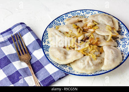 Traditional Ukrainian dumplings, filled with mashed potato and cabbage. Vareniki with filling. Vegetarian dish. Stock Photo