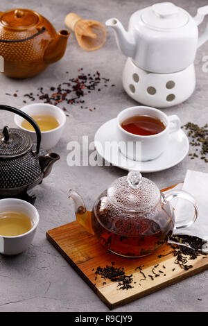 Tea card. Different in appearance teapots on a gray background, different types of tea. Tea still life. Concept. Stock Photo