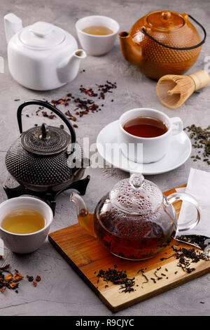 Tea card. Variety of teapots on a gray background, different types of tea. Tea still life. Concept. Stock Photo