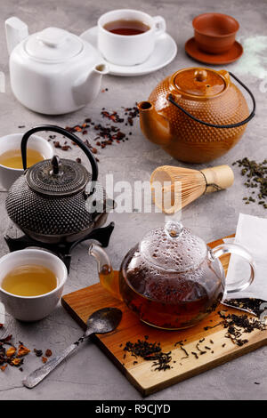 Tea card. Variety of teapots on a gray background and different types of tea. Tea still life. Concept. Stock Photo