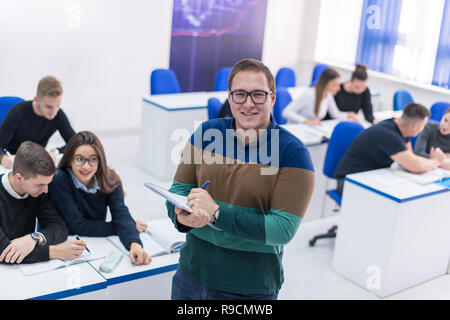 young male student with others writing notes in the classroom Stock Photo