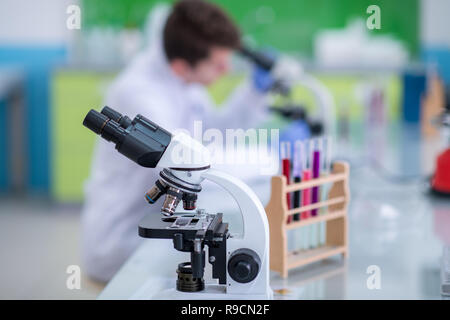 Young student scientist looking through a microscope while doing some research in the laboratory Stock Photo