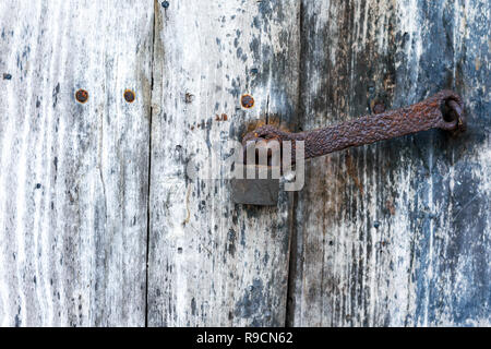 Old rusty padlock in the closed position, hanging on the wooden door Stock Photo