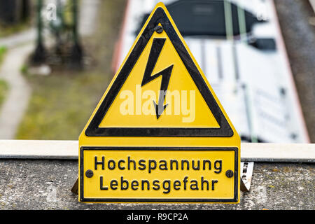 Close-up of a yellow high voltage caution sign mounted on a wall Stock Photo