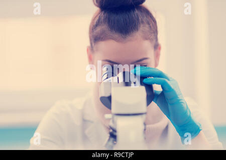 Young female student scientist looking through a microscope while doing some research in the laboratory Stock Photo