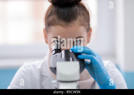 Young female student scientist looking through a microscope while doing some research in the laboratory Stock Photo