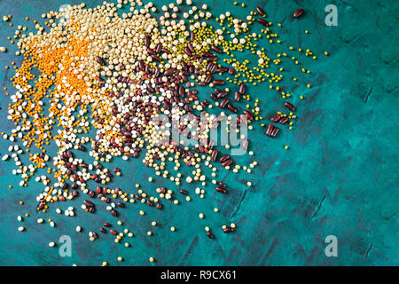 Healthy food theme background. Bunch of scattered beans on emerald green background with copy space. Top view, flat lay. Superfoods are red and white  Stock Photo