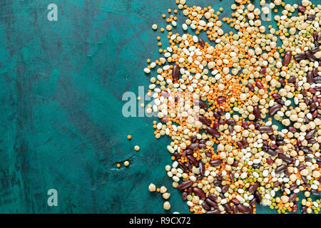 Healthy food theme background. Different beans are lying on emerald green background in the right with copy space. Top view, flat lay. Superfoods are  Stock Photo