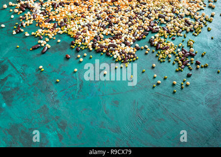 Healthy food theme background. Lot of different beans on top of emerald green background with copy space. Superfoods are red and white haricot, chickp Stock Photo