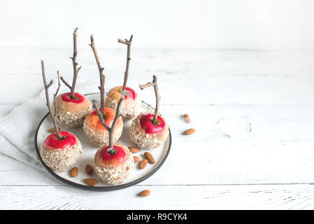 Caramel Apples on Sticks for winter holidays on white wooden background, copy space. Organic Snack, healthy homemade vegan dessert - Caramel Apples wi Stock Photo