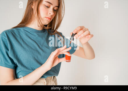 Crop photo of young cute teen girl paints nails isolated on grey background Stock Photo