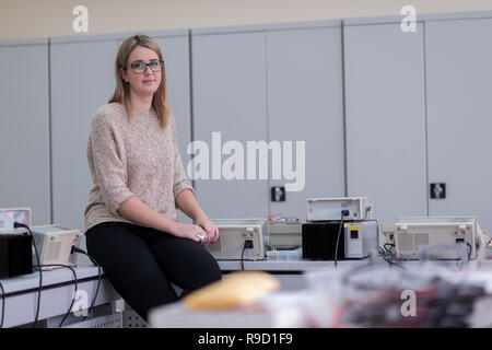 portrait of beautiful young female student sitting on the table at electronics laboratory classroom Stock Photo