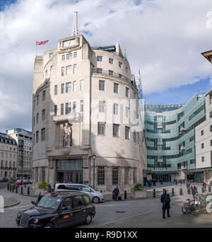 Exterior of BBC broadcasting House and the new Broadcasting House in central London, including stationary taxis and people crossing the courtyard. Stock Photo