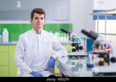 Young student scientist looking through a microscope while doing some research in the laboratory Stock Photo