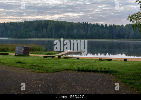 picnic area by the lake with wooden plank boardwalk in sunset with calm water Stock Photo