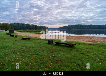 picnic area by the lake with wooden plank boardwalk in sunset with calm water Stock Photo