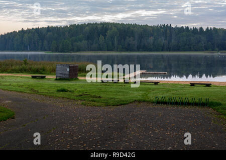 picnic area by the lake with wooden plank boardwalk in sunset with calm water Stock Photo