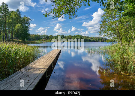 picnic area by the lake with wooden plank boardwalk in sunset with calm water Stock Photo