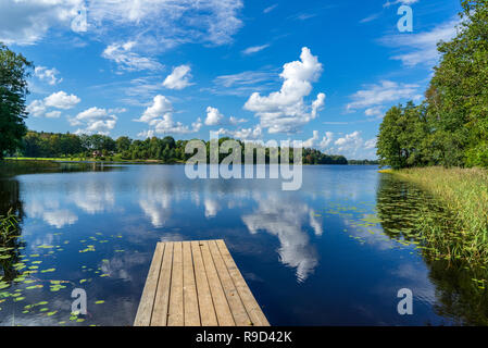 picnic area by the lake with wooden plank boardwalk in sunset with calm water Stock Photo