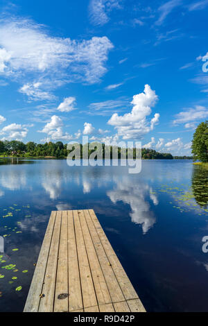 picnic area by the lake with wooden plank boardwalk in sunset with calm water Stock Photo