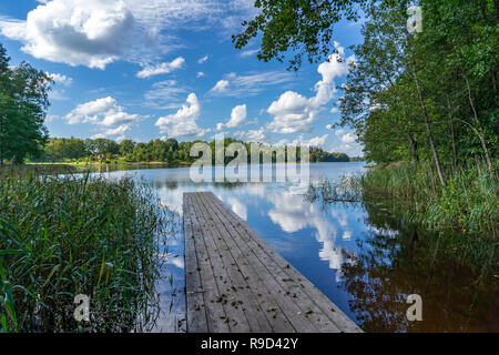 picnic area by the lake with wooden plank boardwalk in sunset with calm water Stock Photo