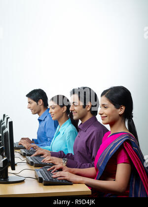 MEN AND WOMEN WORKING ON COMPUTERS IN AN OFFICE/CALL CENTRE Stock Photo