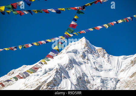 Prayer flags and the summit of Manaslu, the world's 8th highest mountain, in the Nepal Himalayas Stock Photo