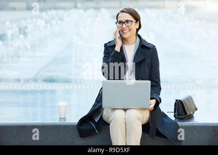 Cheerful freelance consultant talking on phone Stock Photo
