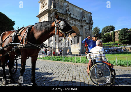 ROME, Italy – October 09, 2018:  A Man in wheelchair enjoying outdoors roman vacations. On the background the Arch of Constantine and the horse for th Stock Photo