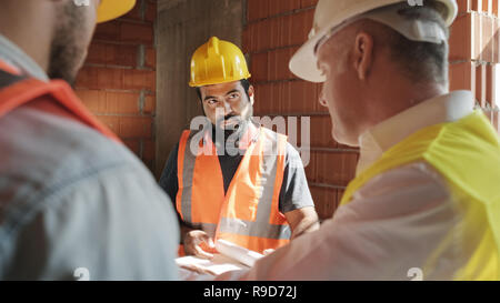Supervisor Showing Building Plans To Workers In New House Stock Photo