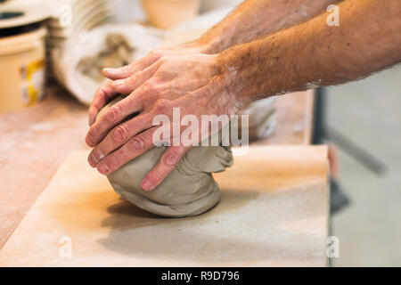 Artist potter in the workshop preparing material for a ceramic vase. Hands detail closeup. Small artistic craftsmen business concept. Stock Photo