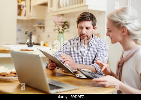 Young couple discussing finances at kitchen Stock Photo