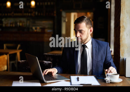 Busy man using laptop in cafe Stock Photo